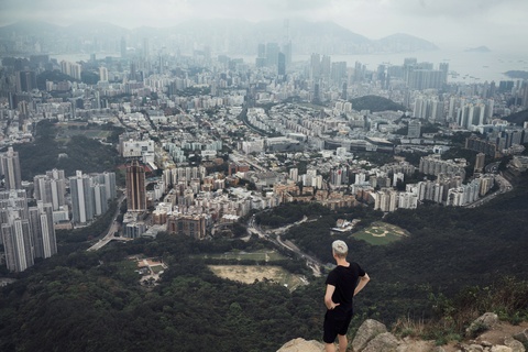 Hoher Blickwinkel eines Mannes, der auf einem Felsen stehend das Stadtbild betrachtet, lizenzfreies Stockfoto