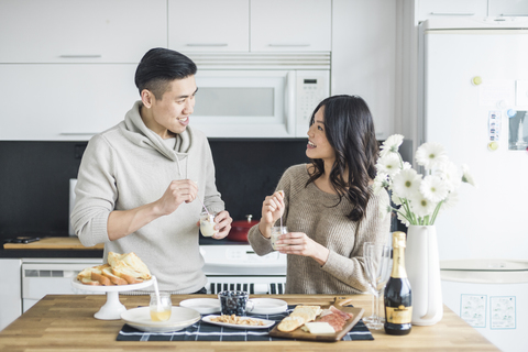 Glückliches Paar sieht sich beim Frühstück in der Küche an, lizenzfreies Stockfoto