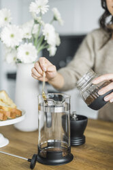 Mittelteil einer Frau, die zu Hause Kaffee in einer französischen Presse zubereitet - CAVF29801