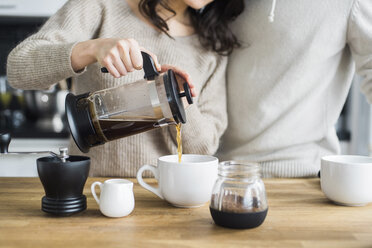 Mittelteil einer Frau mit Freund, die am Tisch Kaffee in Tassen einschenkt - CAVF29803