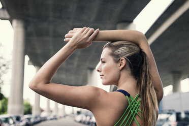 Rückansicht einer selbstbewussten Sportlerin, die ihre Arme unter einer Brücke ausstreckt - CAVF29808