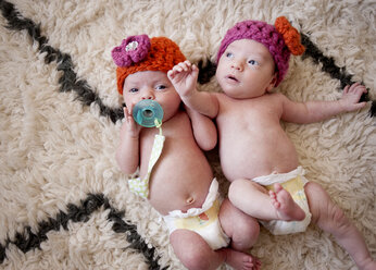 Overhead view of baby girls lying on rug - CAVF29846