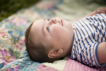 Seitenansicht eines kleinen Mädchens auf einer Decke auf der Wiese liegend - CAVF29850