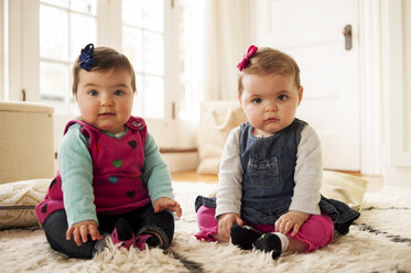 Porträt von niedlichen Baby-Mädchen sitzen auf Teppich zu Hause - CAVF29854