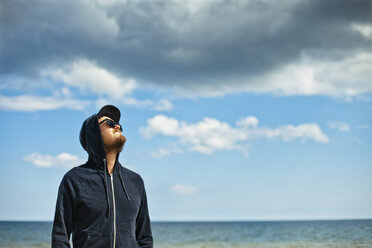 Portrait of man in hooded shirt looking at sky - FOLF02073