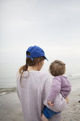 Mother carrying daughter on beach - FOLF02096