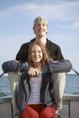 Porträt eines Teenagers und eines jungen Mannes auf einem Boot sitzend, lizenzfreies Stockfoto