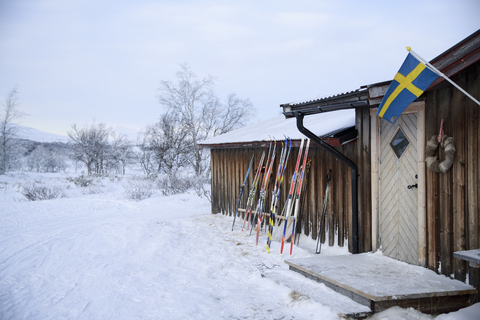 Skier lehnen im Winter an einem Holzchalet, lizenzfreies Stockfoto