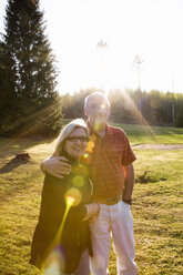 Mann und Frau stehen zusammen auf einer Wiese im Sonnenlicht - FOLF02148