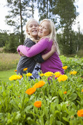 Two girls standing in yellow flowers and hugging - FOLF02152
