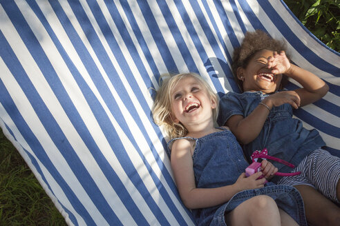 Zwei Mädchen liegen in einer gestreiften Hängematte und lachen - FOLF02155