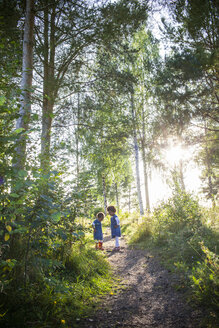 Zwei Mädchen in Jeanskleidern stehen im Wald - FOLF02158