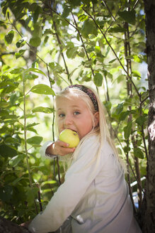 Porträt eines blonden Mädchens, das einen Apfel isst - FOLF02164