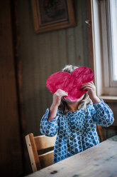 Girl holding paper heart in front of face - FOLF02228