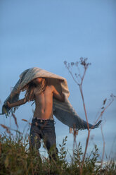 Mädchen steht auf einer Wiese und hält sich eine Decke über den Kopf - FOLF02232