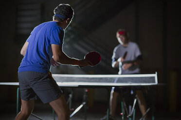 Freunde spielen Tischtennis vor beleuchtetem Gebäude - CAVF29902