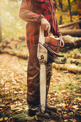 Low section of lumberjack holding chainsaw in forest - CAVF29939