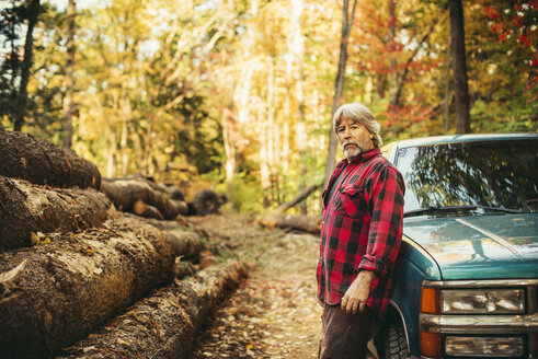 Seitenansicht Porträt eines Holzfällers, der neben einem Auto im Wald steht - CAVF29942