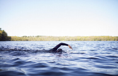 Frau schwimmt im See gegen klaren Himmel - CAVF29969