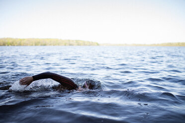 Ausgeschnittenes Bild einer im See schwimmenden Frau gegen den klaren Himmel - CAVF29970