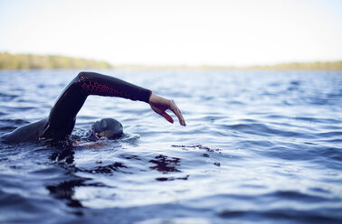 Cropped image of woman swimming in lake against sky - CAVF29972