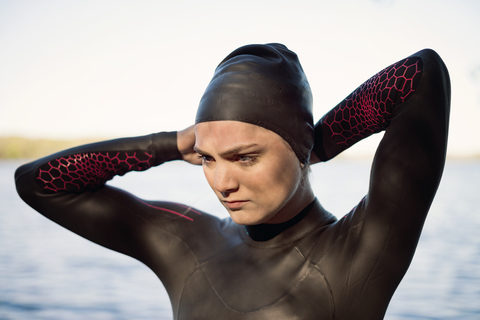 Nachdenkliche Schwimmerin mit Badekappe am Seeufer, lizenzfreies Stockfoto