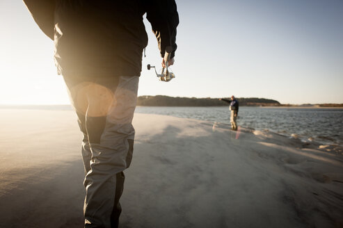 Männer bereiten sich bei Sonnenuntergang am Strand auf das Fischen vor - CAVF30008