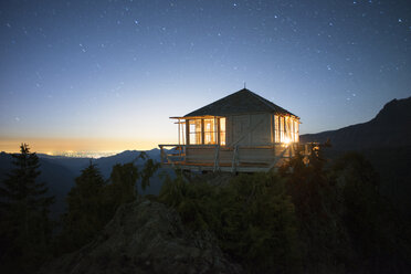 Beleuchtete Hütte auf einer Klippe gegen den Himmel in der Abenddämmerung - CAVF30033