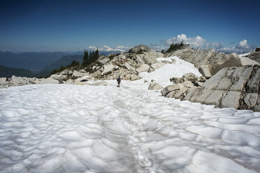 Entfernte Ansicht eines Mannes, der auf einem schneebedeckten Berg gegen den Himmel läuft - CAVF30044