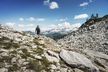 Rear view of man hiking on mountain against sky - CAVF30045