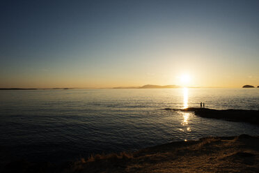 Silhouette von Vater und Sohn am Ufer der Strait of Georgia bei Sonnenuntergang - CAVF30069