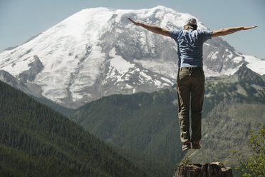 Mann springt mit ausgestreckten Armen gegen den Mount Rainier - CAVF30098