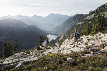 Rückansicht eines Mannes, der auf einer Klippe vor einer Bergkette steht - CAVF30104