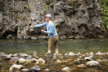 Man fishing at river against rocks - CAVF30119