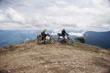 Freunde fahren Motorrad auf Klippe gegen bewölkten Himmel - CAVF30125