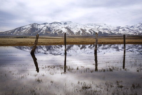 See umgeben von Zaun durch schneebedeckten Berg gegen bewölkten Himmel - CAVF30160
