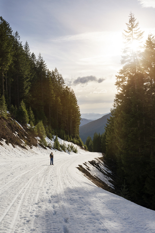 Mittlere Entfernung eines Mannes, der auf einem schneebedeckten Wanderweg auf einem Berg im Gifford Pinchot National Forest steht, lizenzfreies Stockfoto