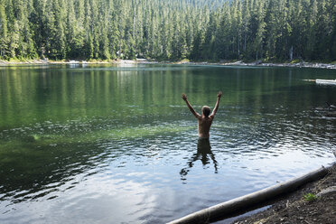 Man with arms raised standing in lake - CAVF30188