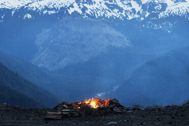 Campfire on field against snowcapped mountains - CAVF30196