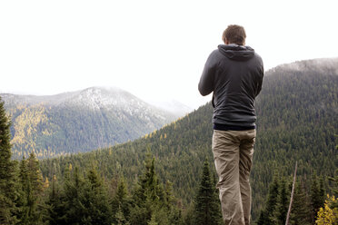 Rear view of man standing on mountain against clear sky - CAVF30206