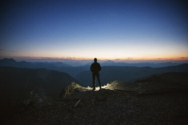 Rear view of man standing on mountain against sky during sunset - CAVF30223