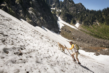 Side view of man walking with dog on snowcapped mountain - CAVF30241