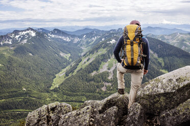 Rear view of hiker standing against mountain range - CAVF30247