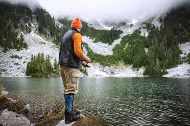 Rückansicht eines Mannes beim Fischen am See gegen die Berge - CAVF30254