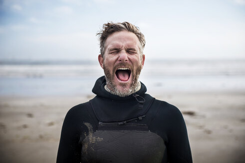 Männlicher Surfer, der schreiend am Strand steht - CAVF30262