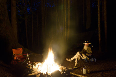Mann entspannt sich am Lagerfeuer im nächtlichen Wald - CAVF30285