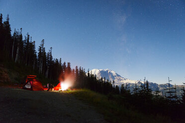 Beleuchtetes Zelt auf einem Hügel am Waldrand gegen den nächtlichen Himmel - CAVF30325