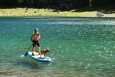 Hohe Winkel Ansicht der Mann paddalboarding mit Hund auf See - CAVF30327