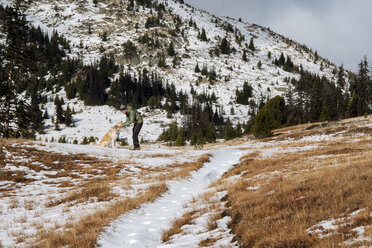 Glücklicher Mann, der seinen Hund streichelt, während er im Winter auf einem Feld steht - CAVF30350