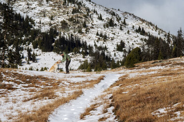 Happy man stroking dog while standing on field during winter - CAVF30350